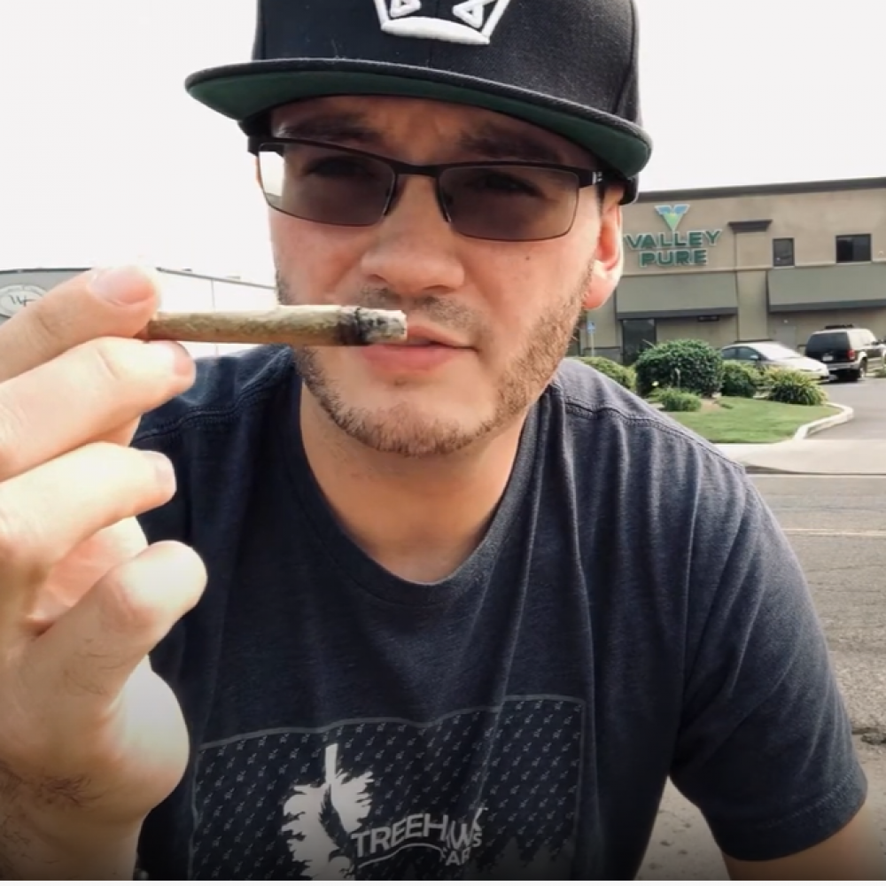 RMR Joey holding a lit Biscotti Pre-roll joint