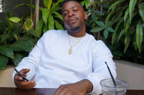 a photo of yohiness sitting at a table with a beverage in a white shirt