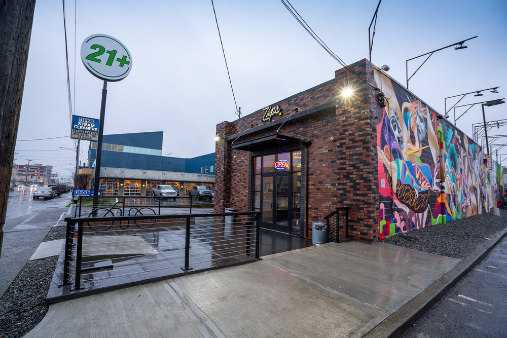 Zips Sodo Storefront, large brick building with glass doorway and graffiti side wall