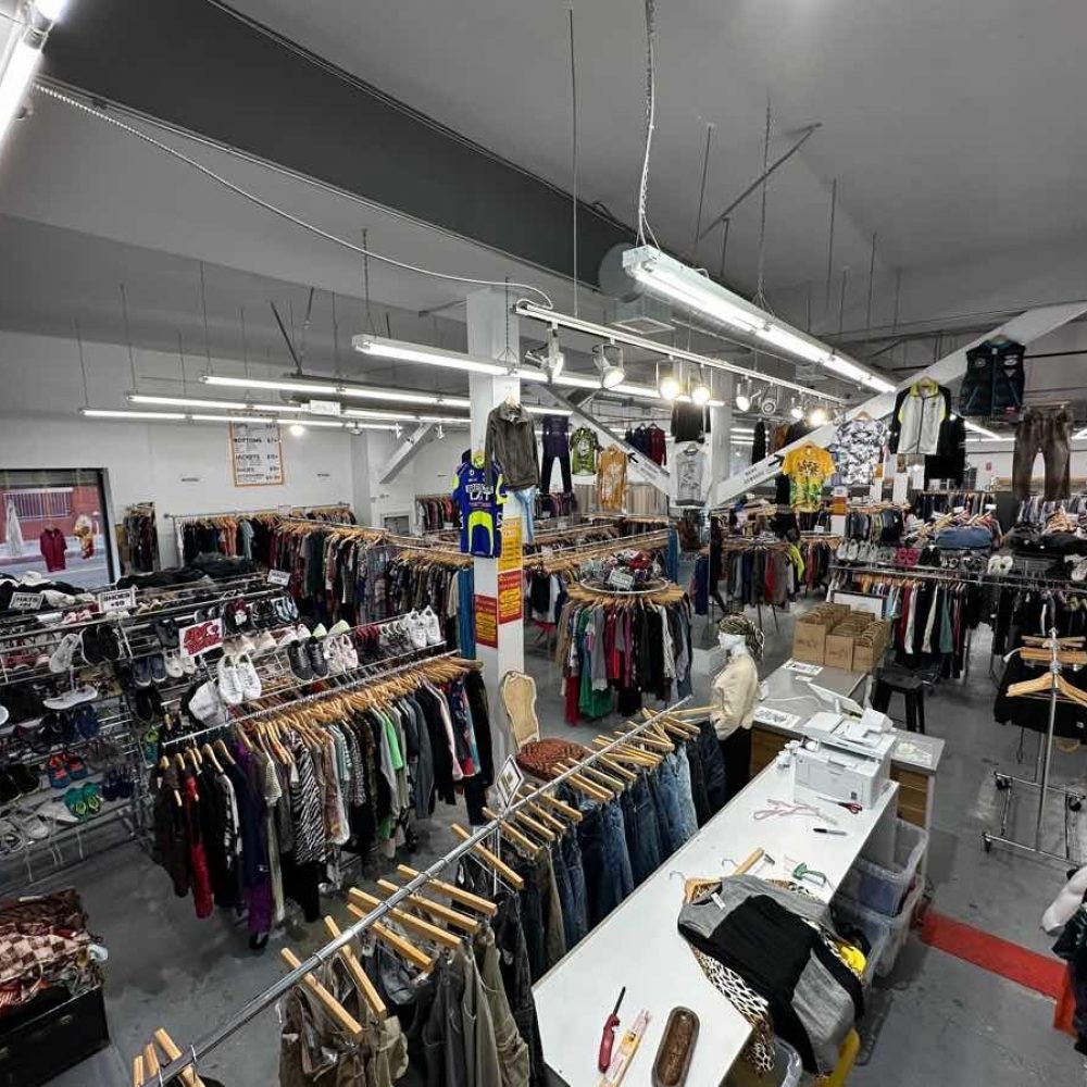 Interior photo of the thrift store Public Estrellas displaying various racks of clothing. 